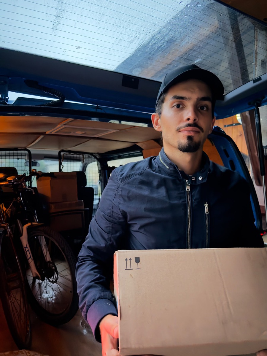Votre déménageur à Blois portant un carton, face caméra, devant son véhicule de déménagement